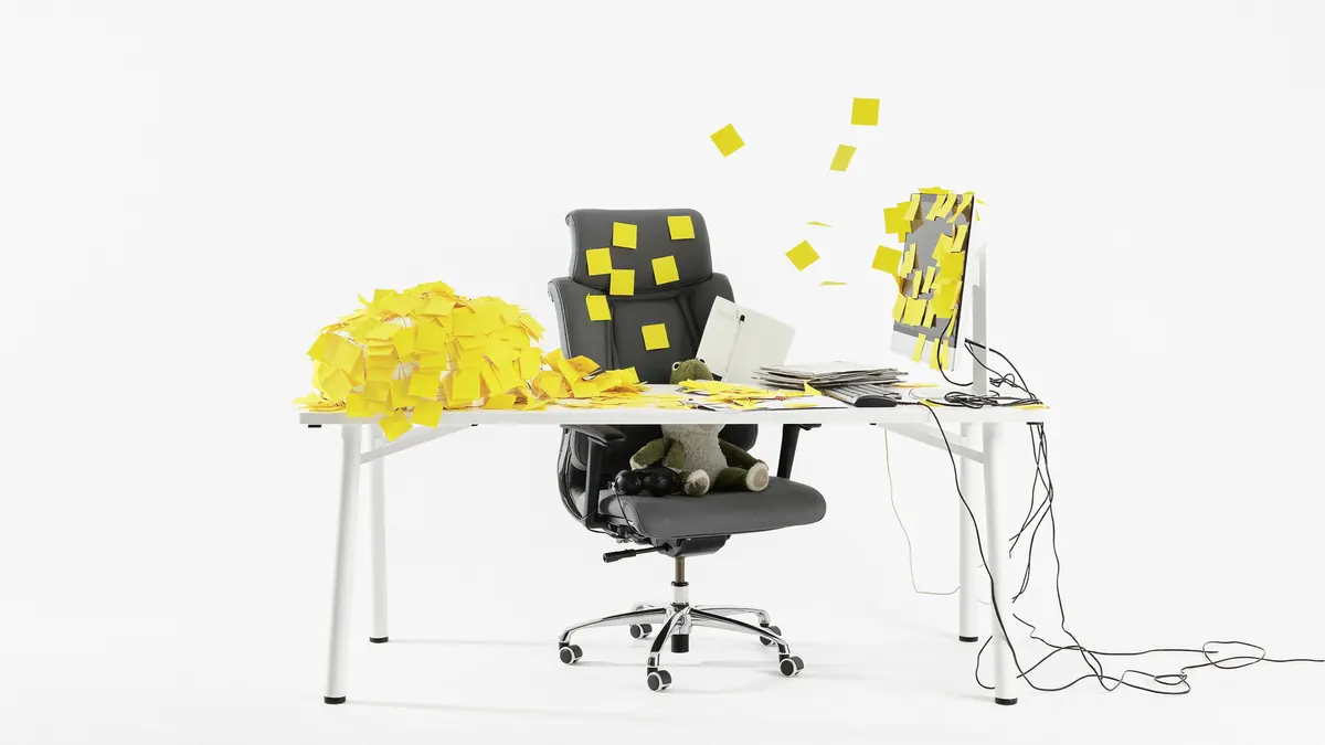 Un poste de travail enseveli sous des post-it jaunes qui s'envolent de l'écran et du fauteuil.