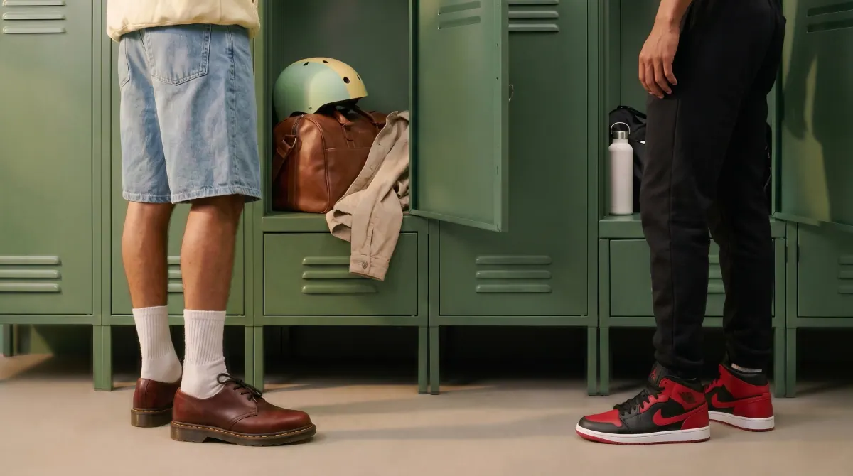 Devant des casiers d'école, les jambes d'un enfant en short face à celles d'un adulte